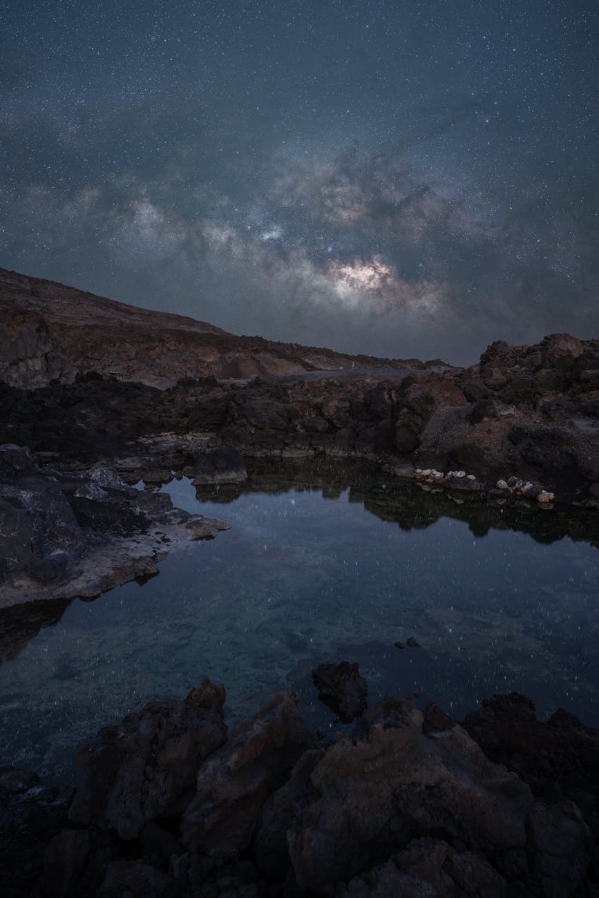 view of a body of water and rocky mountains under a night sky